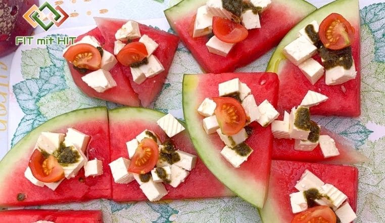 Melonenscheiben mit Feta, Tomaten und Pesto